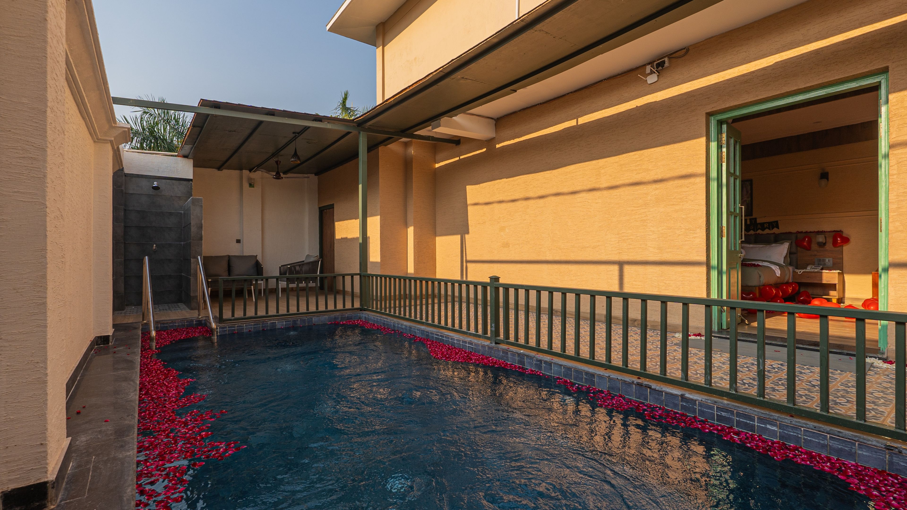 Piscina com deck revestido e pequena área de estar com cadeiras.