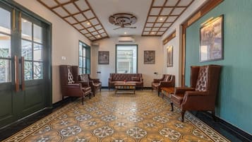 A hallway with patterned flooring, leather furniture, and framed artwork on the walls.