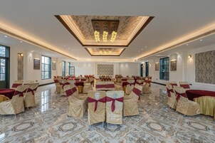 A spacious hall with rows of chairs and tables, a marble floor, and a ceiling with a light fixture.