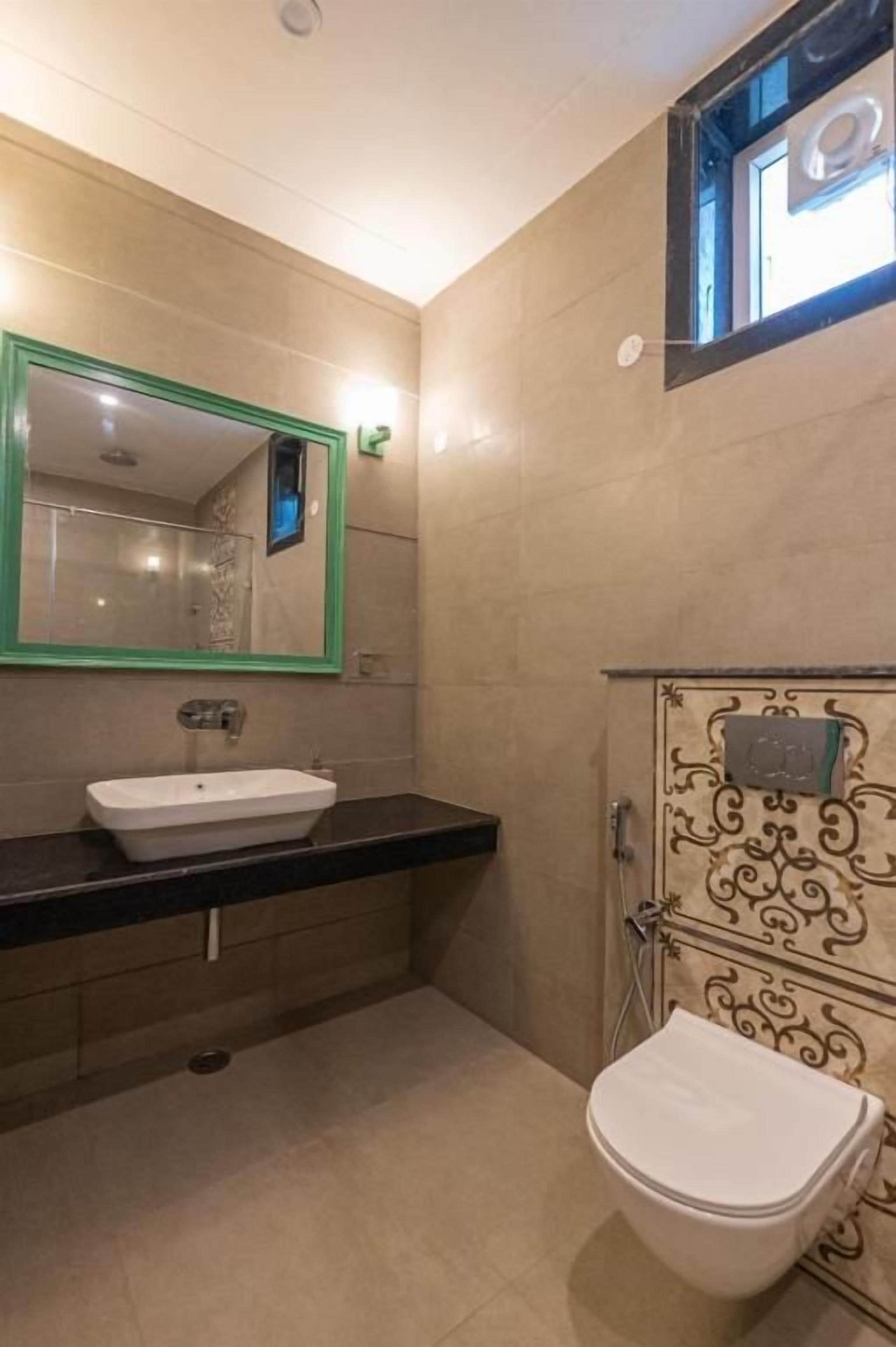 Un baño con lavamanos blanco, espejo y retrete.