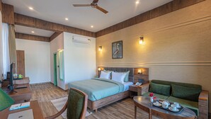 A hotel room with a bed, a green sofa, a desk with a laptop, a tray with cups and a teapot, and a painting on the wall. - Trideus The Wild Fraser Corbett (Kaladhungi)
