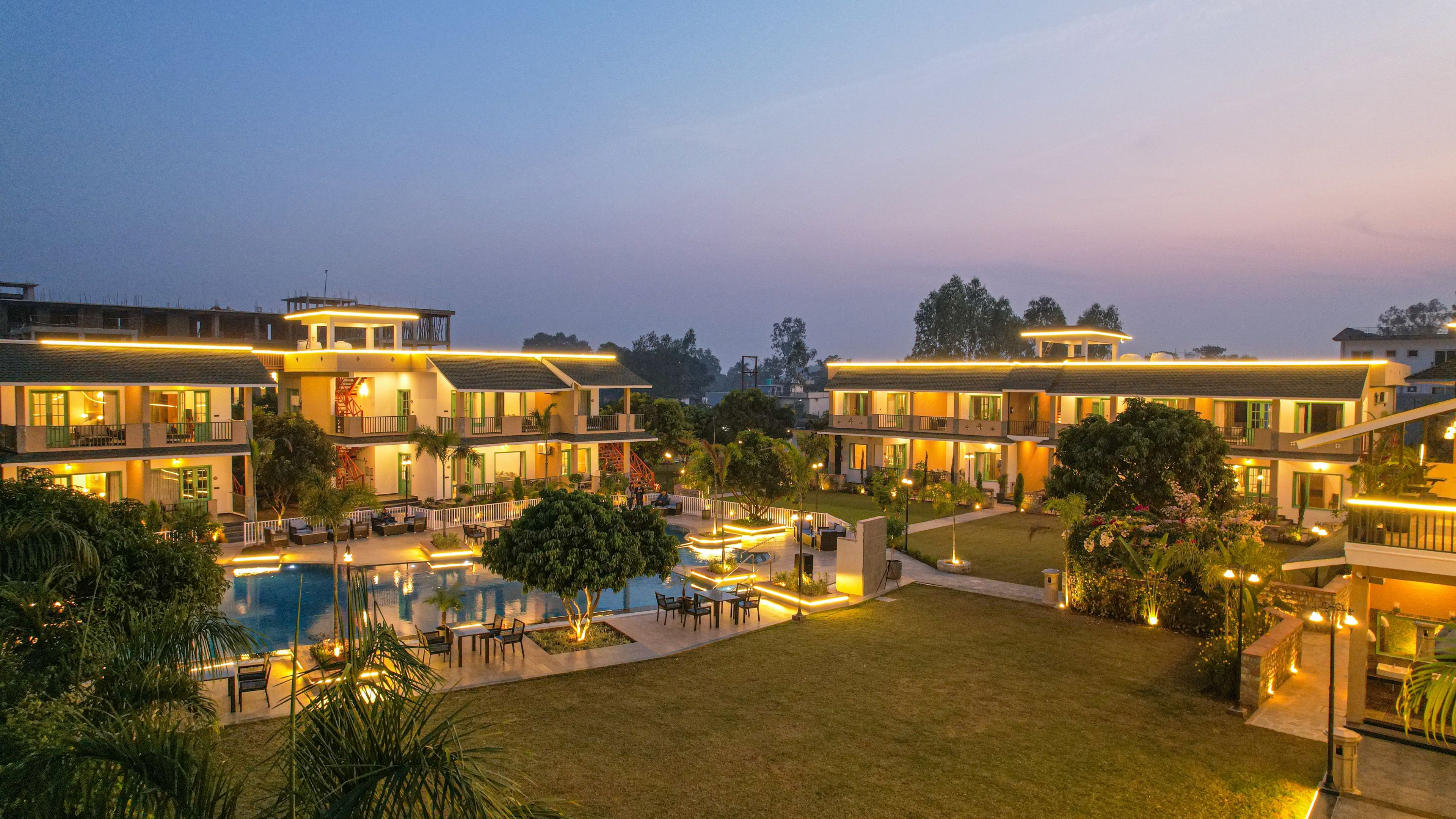 Ein Resort mit mehreren Gebäuden, einem Schwimmbad und gut beleuchteten Außenbereichen.
