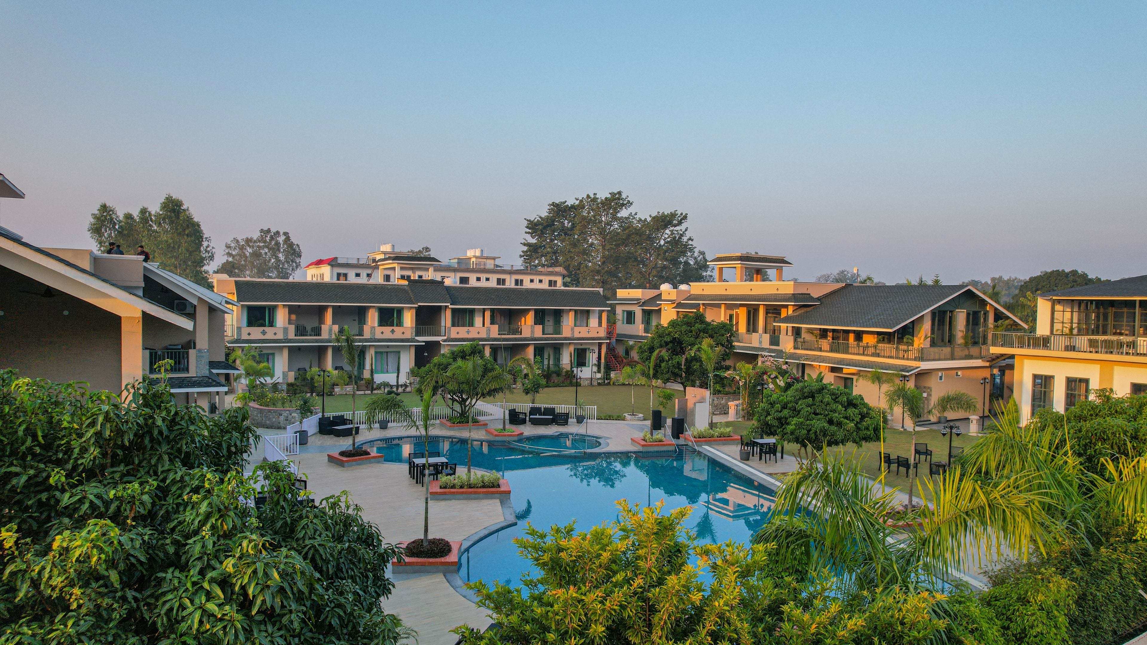 Ein Hotel mit Swimmingpool, mehreren Balkonen und üppiger Bepflanzung.