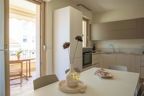 Eine moderne Küche mit Essbereich, einer Vase mit getrockneten Blumen und Blick auf den Balkon.