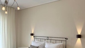 Un lit bien fait, avec du linge de lit blanc, deux tables de chevet avec des lampes et un lustre moderne.