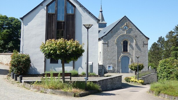 A church with a prominent steeple and a large clock. - Spacious gite in Somme-leuze (Heure)
