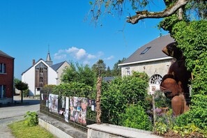 Een straat met een kerk, een gebouw met een klok en een groot beeldhouwwerk.