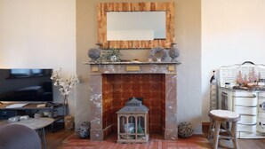 A living room with a fireplace, a television, and a dining area with a table and chairs. - Spacious gite in Somme-leuze (Heure)