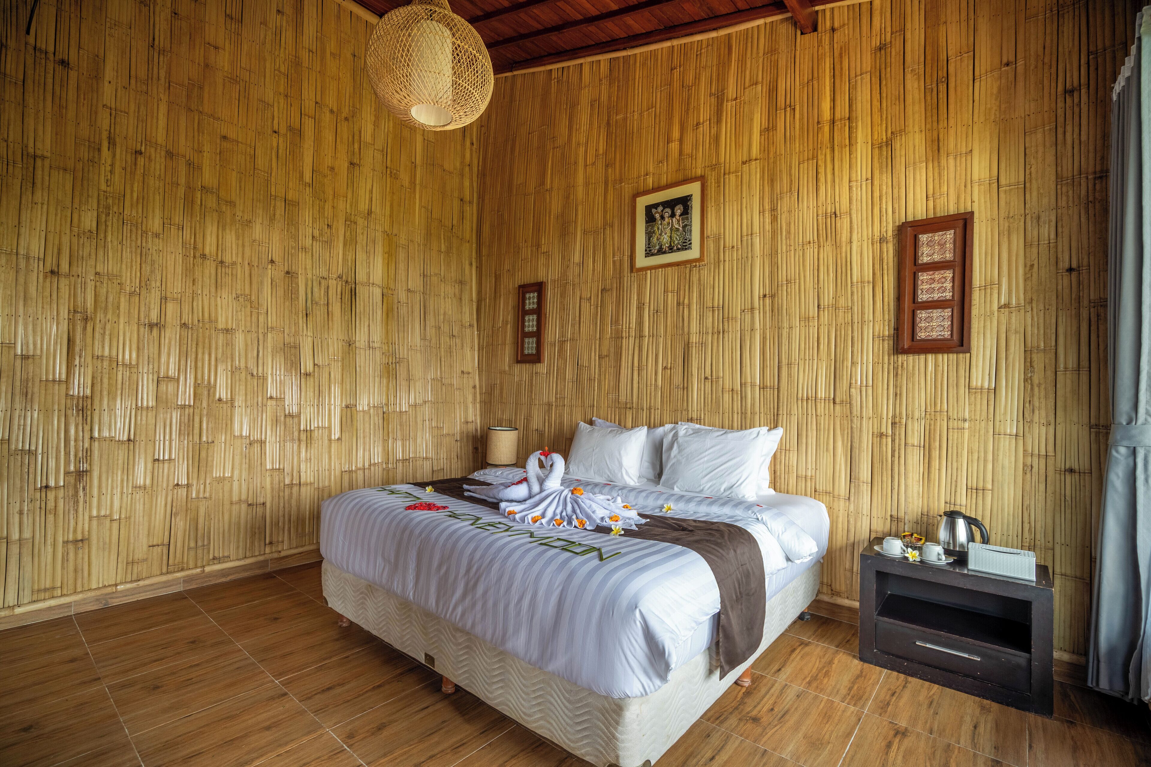 A room with a bed, a nightstand, and a woven bamboo wall.