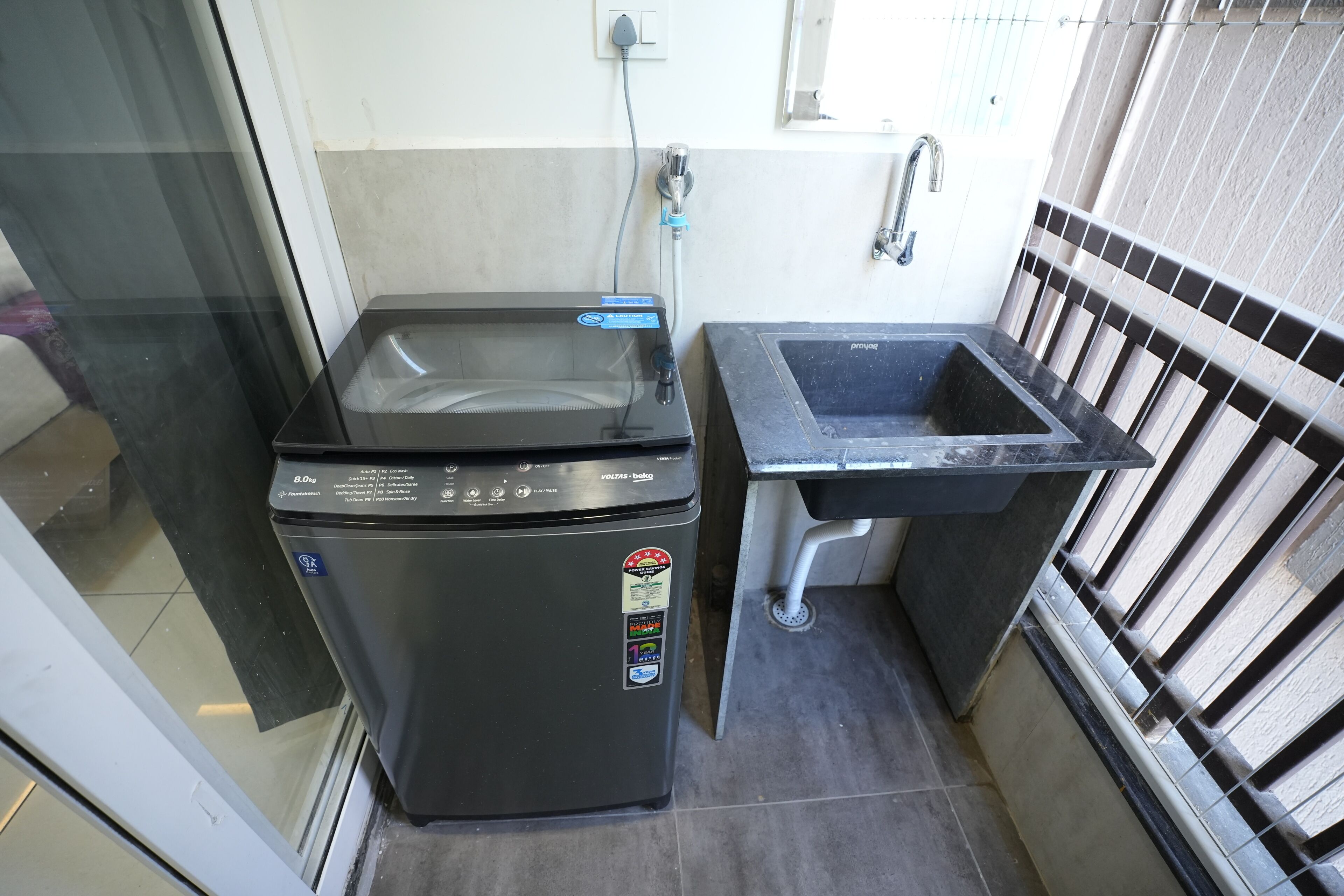 Cocina compacta con lavadora integrada, un lavabo y una ventana.