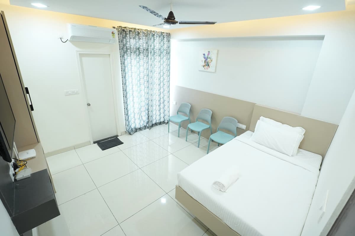 Une chambre d’hôtel avec un lit, un ventilateur de plafond, une fenêtre avec des rideaux et une porte.