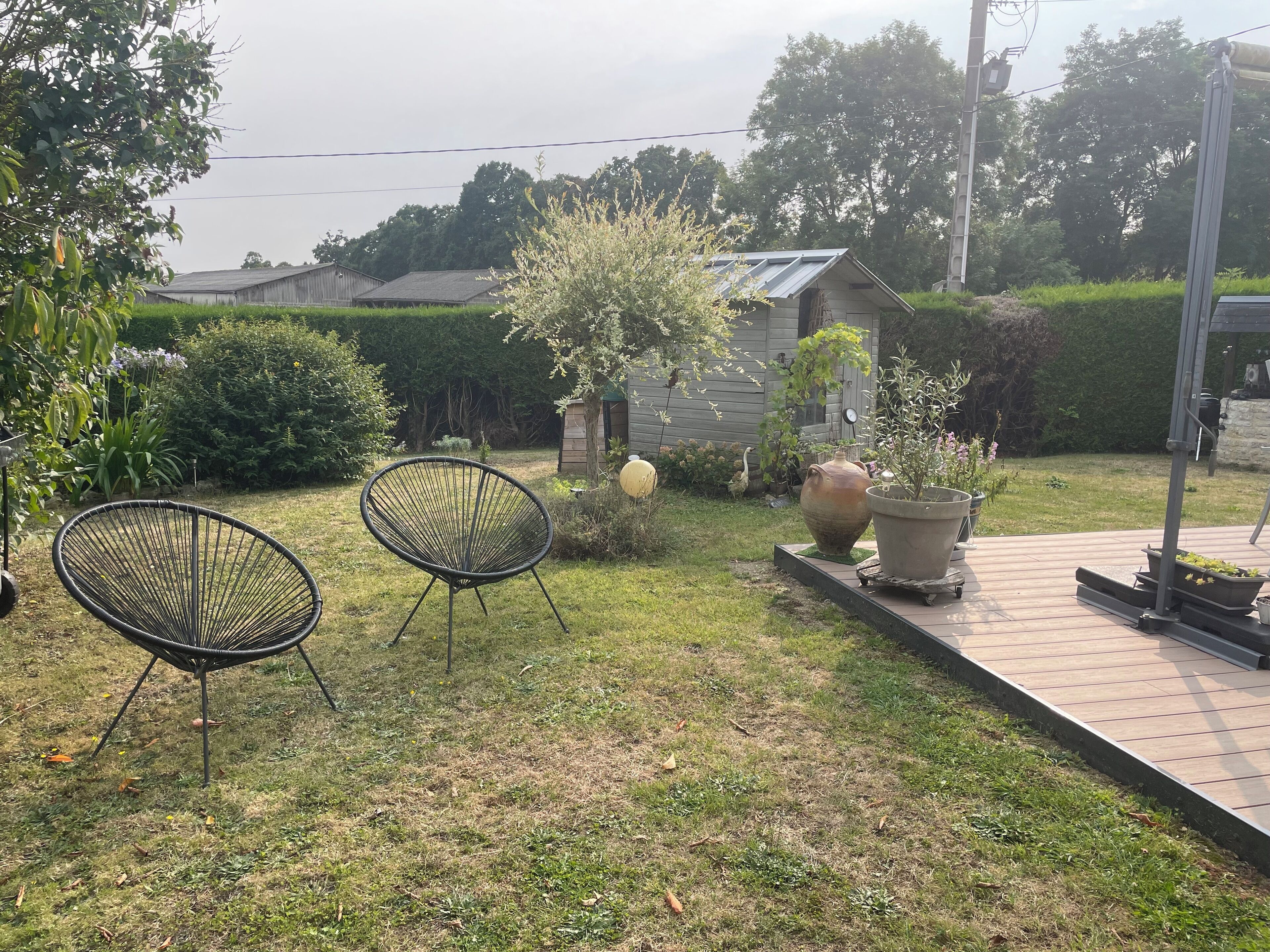 Un jardín con dos sillas, una jardinera grande y una estructura de madera.