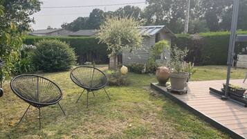 Un jardín con dos sillas, una jardinera grande y una estructura de madera.