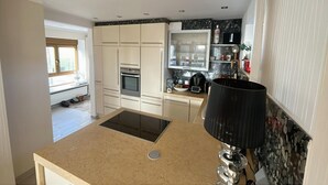 Una cocina moderna con horno empotrado, microondas, fregadero y estufa. Hay una ventana que proporciona luz natural y vistas al exterior.