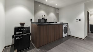 A compact kitchen with a built-in washing machine, a coffee maker, and a compact refrigerator. - J nine Lodge (Seoul)