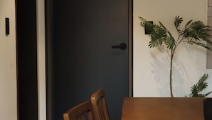 A dining area with a wooden table and chairs, a dark door, and a potted plant. - J nine Lodge (Seoul)