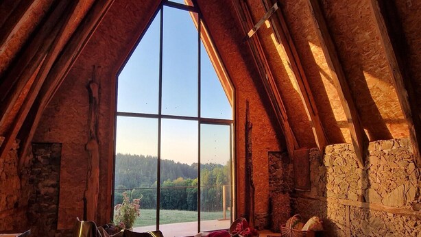 A room with a large skylight, stone walls, and a view of a forested area.