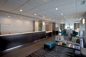A modern lobby with a reception desk, seating area, and a view of the kitchen.