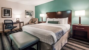 A hotel room with a bed, a desk, a chair, a bench, and two bedside lamps.