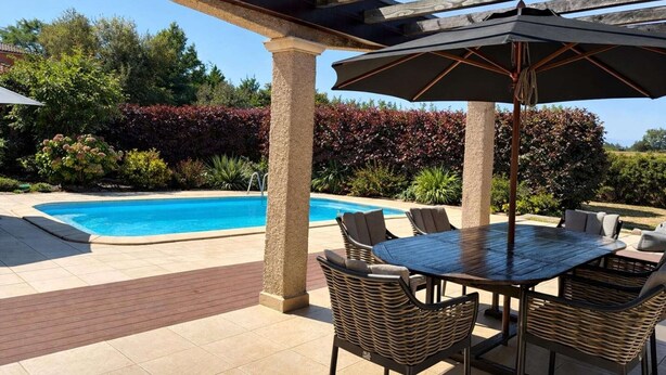 Un espace aménagé au bord de la piscine, avec un patio couvert, du mobilier d’extérieur et une piscine.