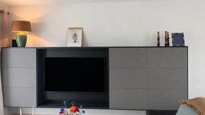 Un salon moderne avec un grand téléviseur à écran plat fixé sur un meuble gris.