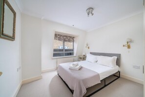 Un dormitorio con cama, ventana con vistas, radiador y lámpara fijada a la pared.