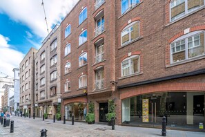 A multi-story brick building with large windows, a storefront, and a pedestrian street. - Bright Two-bed Flat in Covent Garden (London)