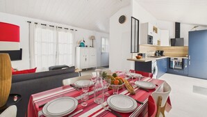 A modern kitchen with a central island, a dining area with a red-striped tablecloth, and a living room with a sofa and a TV. - House for 4 adults 2 children, 30m from the sea (Noirmoutier-en-l´Ile)
