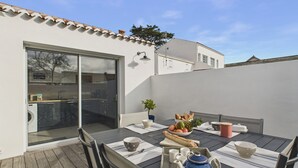 A patio with a dining table set for four, a blue teapot, and a bowl of fruit. - House for 4 adults 2 children, 30m from the sea (Noirmoutier-en-l´Ile)