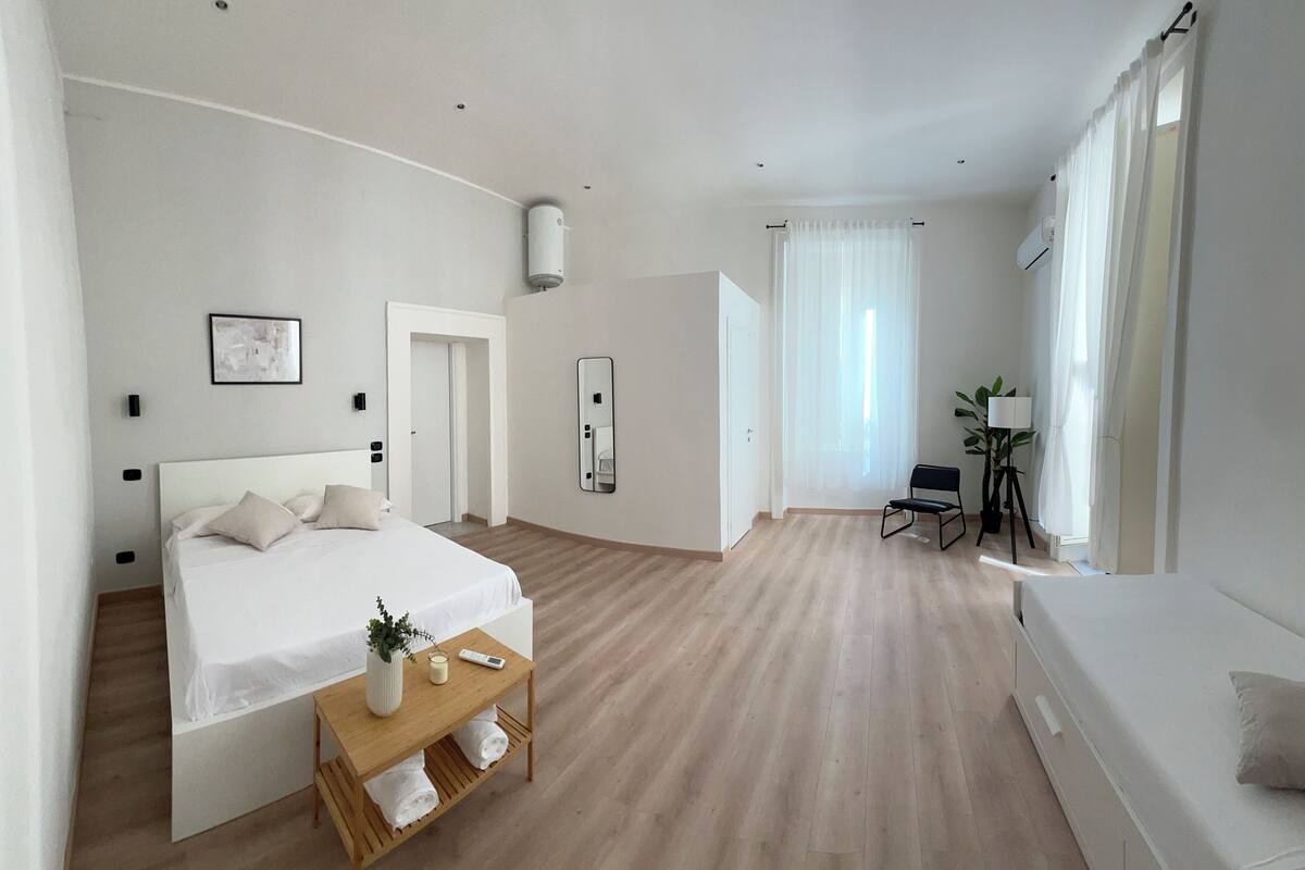 Une chambre spacieuse avec un grand lit, des tables de chevet, un bureau et une chaise.