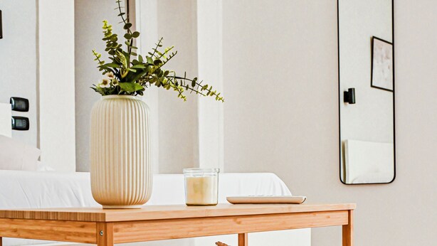 A wooden table with a vase and candles, a mirror, and neatly folded towels on a shelf. - 174 Urban Stay (Naples)