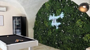 A pool table with balls, a neon sign, and a green wall with plants. - Écrin Caché suite with pool table and island bath (Anduze)