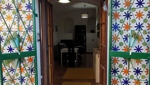 En dør med et farverigt stjernemønstret flisemønster, der fører ind i et rum med en seng og et skrivebord.