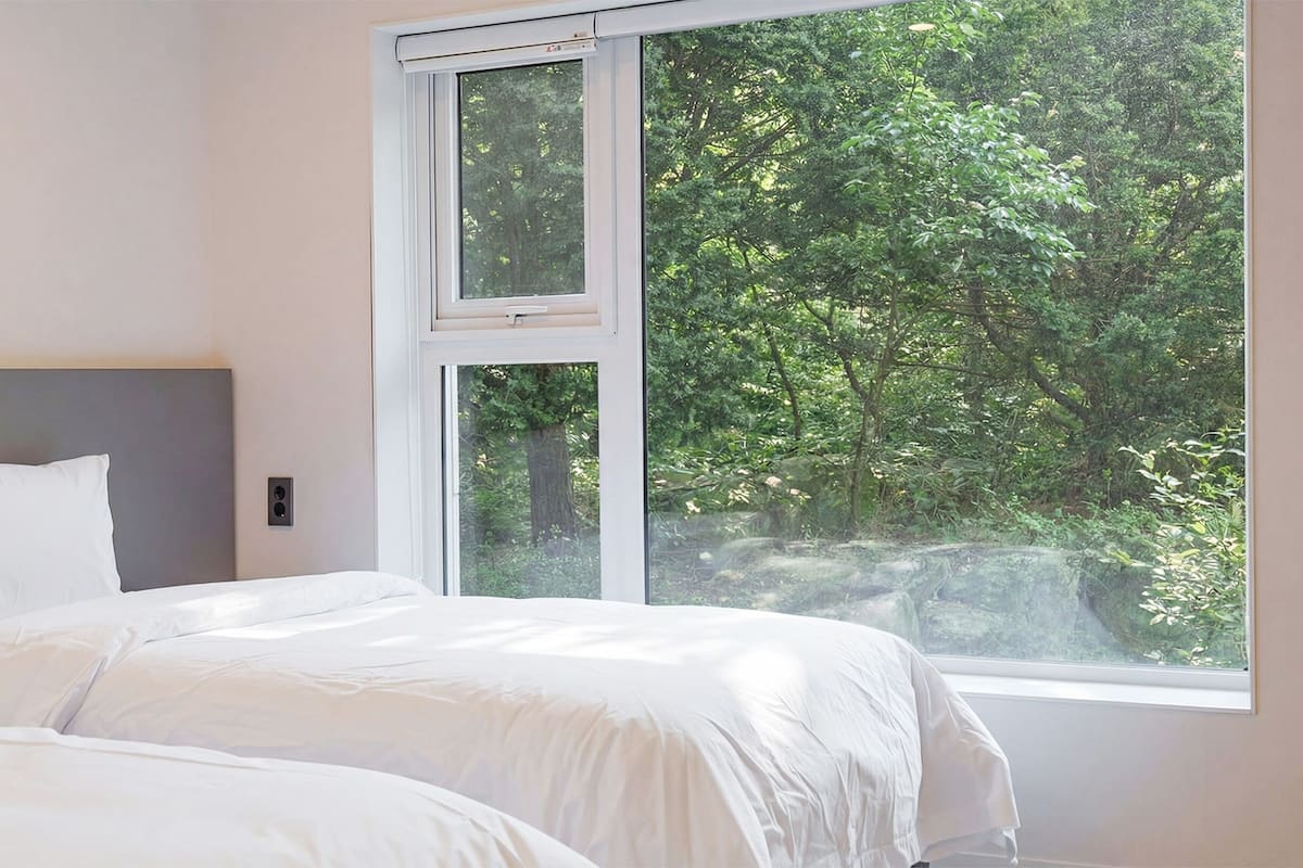 A bedroom with a large window, a bed, and a headboard.