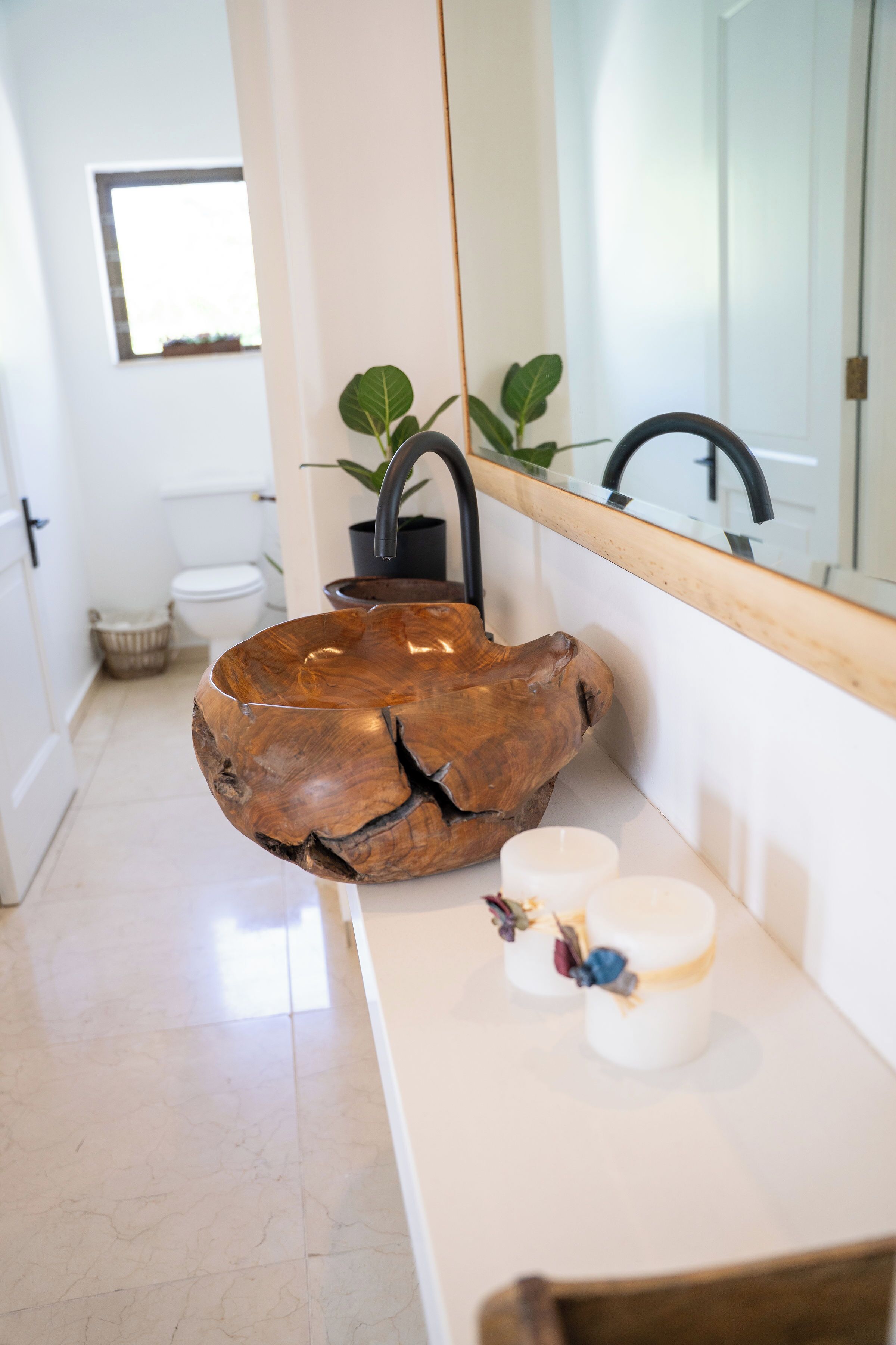 Un baño con lavabo de madera, un espejo y una encimera blanca con dos recipientes pequeños.