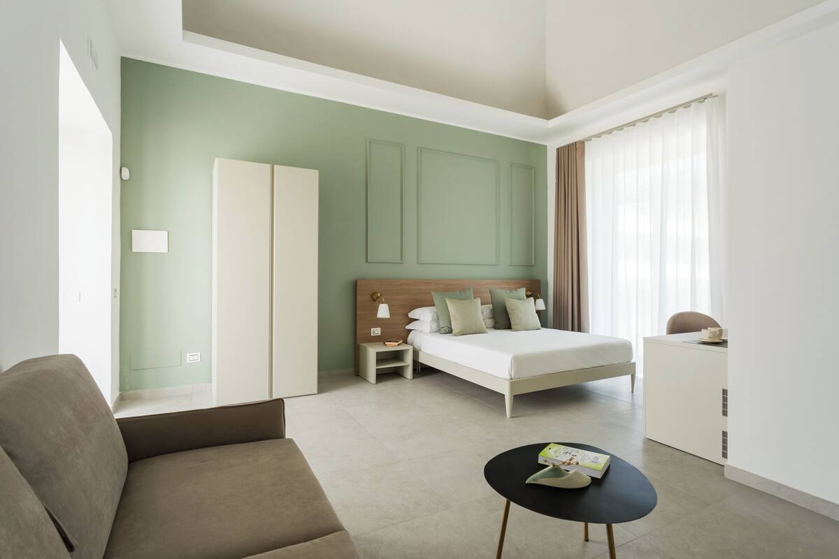Ein modernes Hotelzimmer mit Bett, einer Couch, einem kleinen Tisch und einem Schreibtisch.