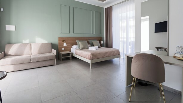 Una habitación de hotel moderna con cama, sofá, escritorio y silla.