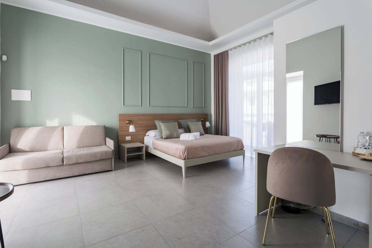 Ein modernes Hotelzimmer mit Bett, Sofa, Schreibtisch und Stuhl.