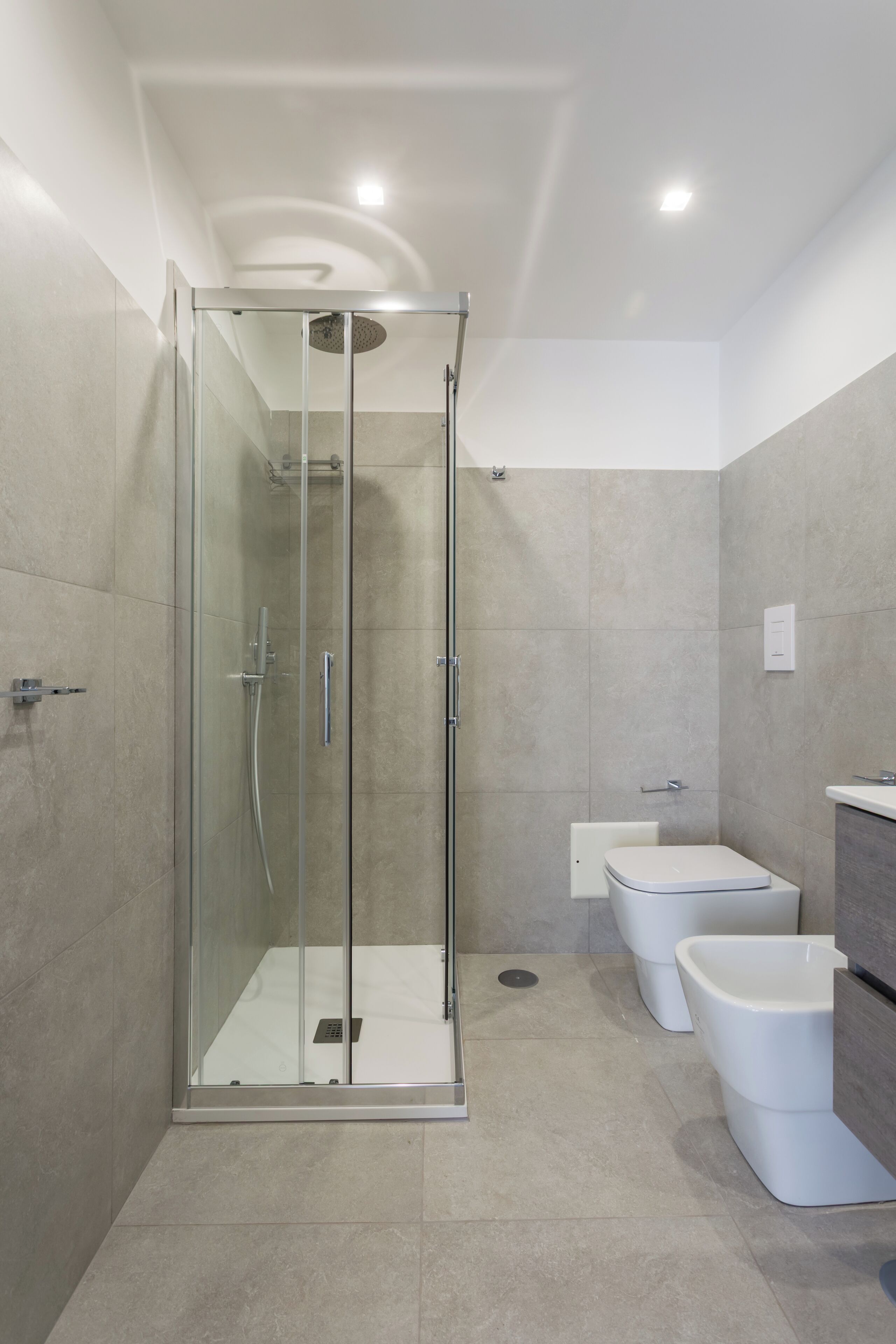 Un baño moderno con ducha envuelta en vidrio, inodoro y bidé.
