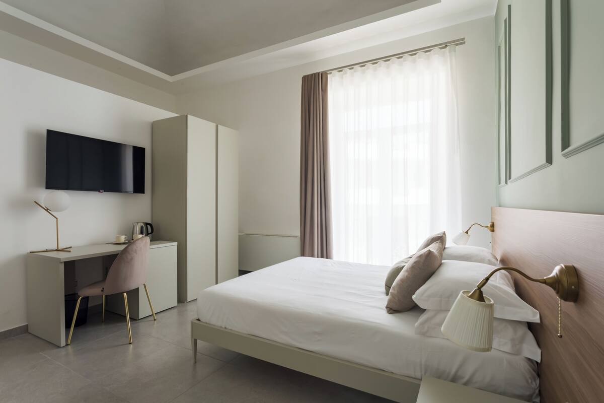 Ein modernes Schlafzimmer mit Bett, Nachttischlampen, Schreibtisch und Fernseher.