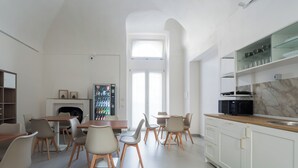 Una cocina moderna con armarios blancos, un comedor con mesas y sillas de madera, y una chimenea.