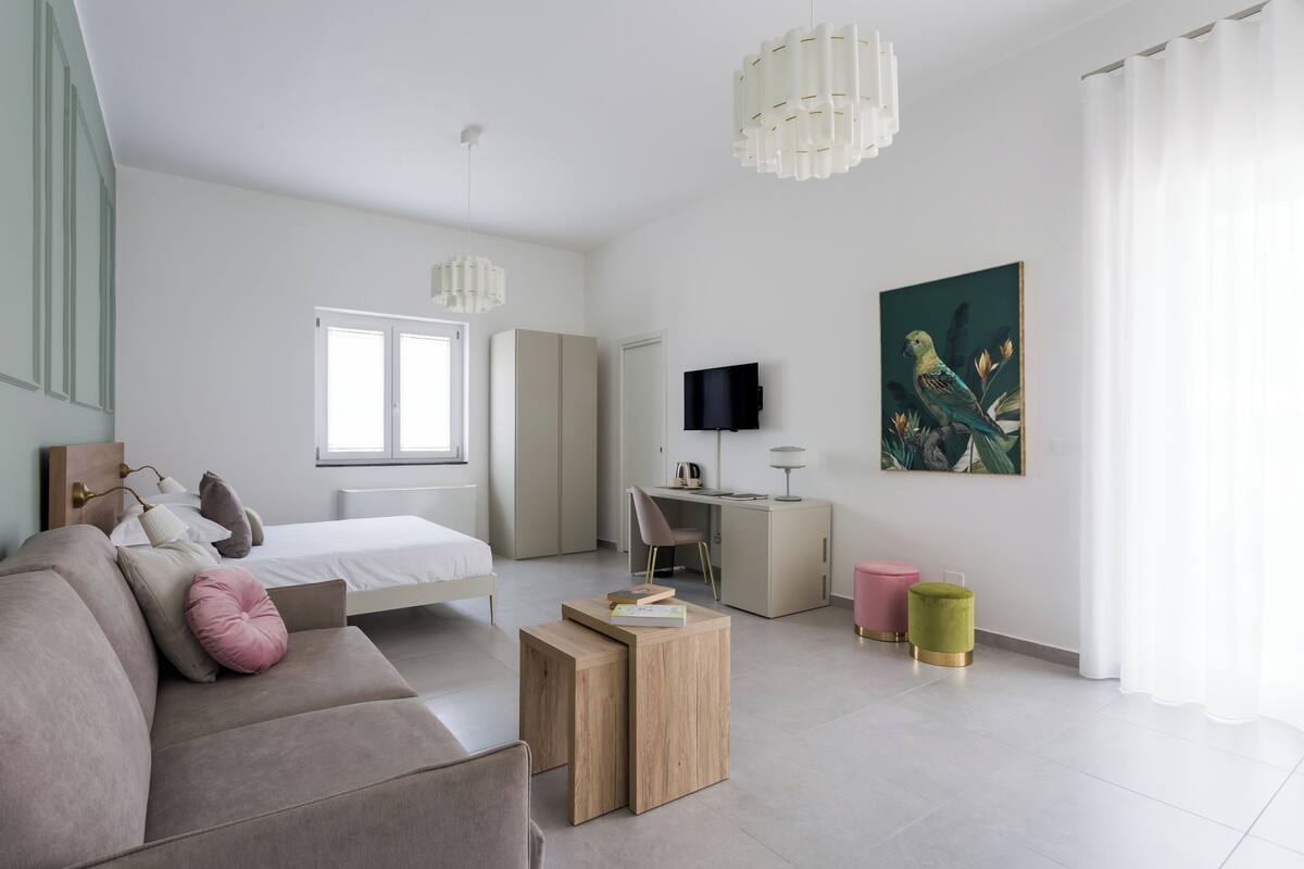 Ein modernes Schlafzimmer mit Bett, Schreibtisch, Fernseher und einem Gemälde.