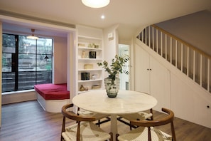 A cozy room with a round table, a bench, and a staircase. - The Architect's House (London)