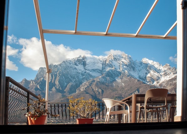 Varanda com vista para montanhas nevadas, plantas em vasos e móveis de exterior.