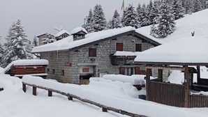 A stone building with a snow-covered roof and a wooden bench in the foreground.