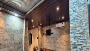 A spa area with a stone wall, wooden ceiling, and a sofa with pillows. - Townhouse Oak Pawana Road Lonavala (Mawal)