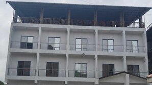 A multi-story building with balconies, large windows, and a covered entrance. - Townhouse Oak Pawana Road Lonavala (Mawal)