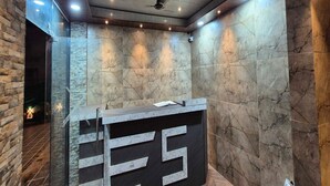 A reception area with a marble wall, a reception desk, and a ceiling with recessed lighting. - Townhouse Oak Pawana Road Lonavala (Mawal)