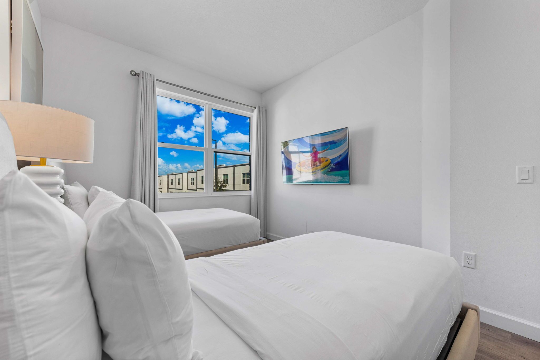 A hotel room with a bed, a sofa, a window with curtains, and a painting on the wall.