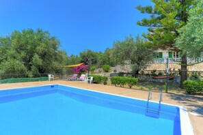 A swimming pool with a ladder, surrounded by greenery and a stone wall. - Frangis Dekatria in Pelekito Corfu (Corfu)